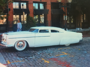 A car parked in the street near the riverfront